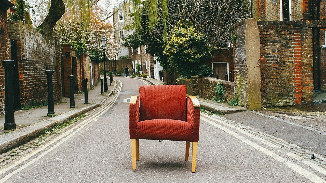 Red armchair placed in the middle of a quiet street”
