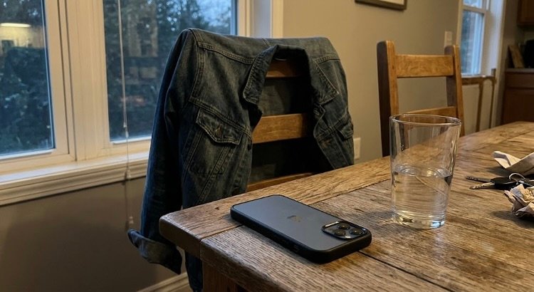 jasje, telefoon en glas water op tafel na thuiskomst